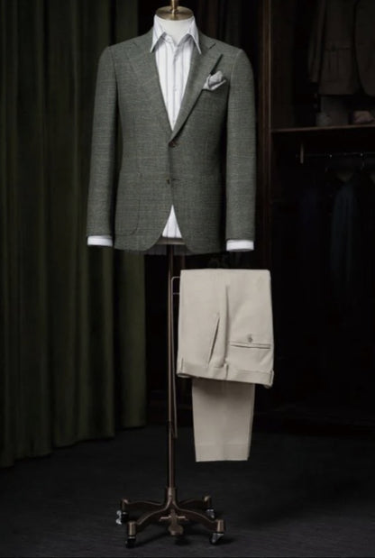 A green and orange check single breasted jacket displayed on a mannequin, with ivory trousers presented below. The jacket features a notched lapel, round patch pockets, and brown front buttons.