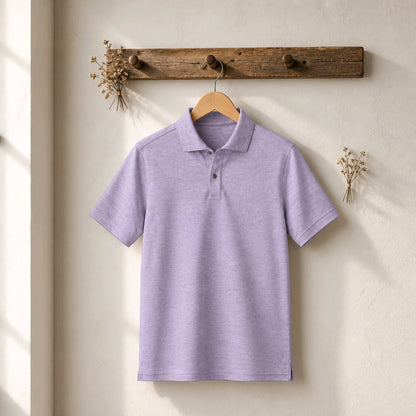 A light grey short-sleeve polo shirt hanging on a wooden hanger from a rustic wooden peg rack against a textured off-white wall.