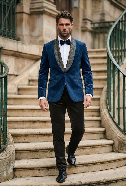 A man walks down a stone staircase wearing a blue velvet tuxedo jacket with gray shawl lapels, black trousers, a white shirt, and a black bow tie.