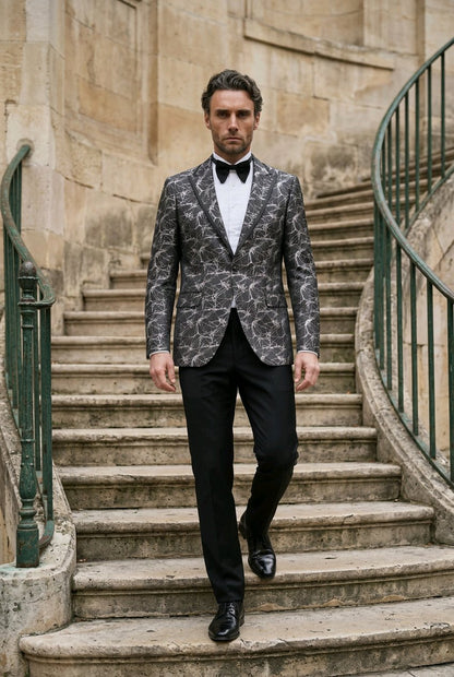 A man walks down a stone staircase wearing a patterned gray and black tuxedo jacket with a white shirt and black bow tie.