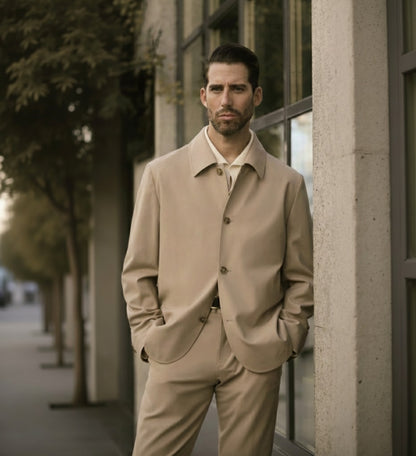A man wearing a beige wool stretch two piece suit with a shirt and tie, standing outdoors.