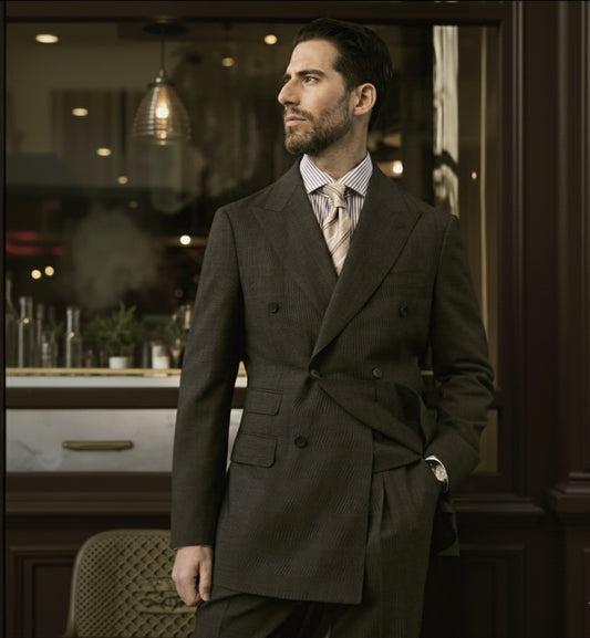 A man wearing a brown double-breasted two-button suit with a peaked lapel, suitable for business or formal occasions.