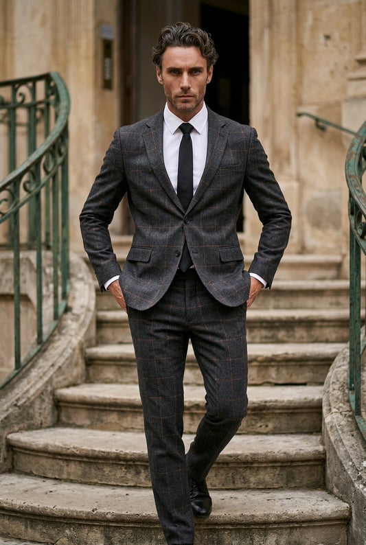 A man wearing a dark gray and black plaid suit with a white dress shirt and black tie, walking down stone stairs in front of a building.