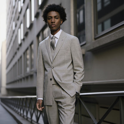 A man wearing a light grey wool two-piece suit with a peaked lapel and navy buttons.