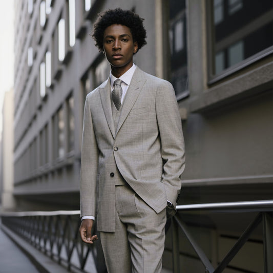 A man wearing a light grey wool two-piece suit with a peaked lapel and navy buttons.