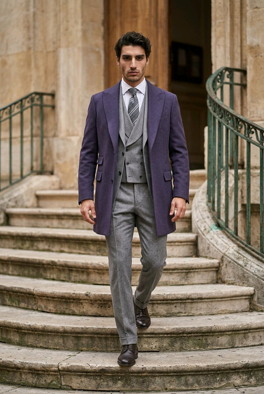 A man wearing a navy overcoat, gray three-piece suit, white dress shirt, and striped tie walks down stone stairs in front of a classical building.