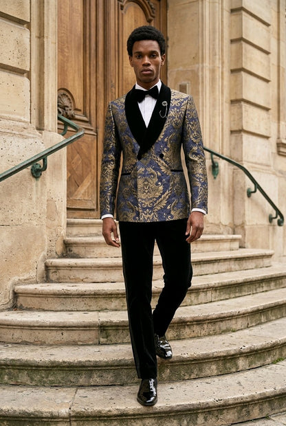 A man wearing a patterned blue and gold tuxedo jacket with black velvet shawl collar, black trousers, and a black bow tie walks down stone steps in front of a classical building.