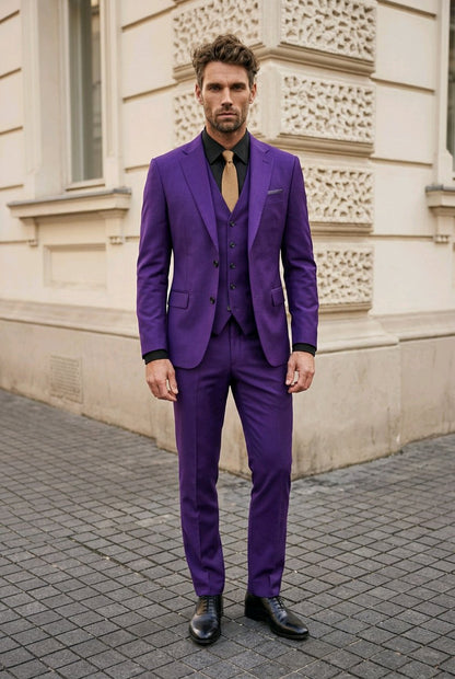 A man wearing a vibrant purple three-piece suit with a black shirt and a gold tie, standing on a cobblestone street in front of a beige stone building.