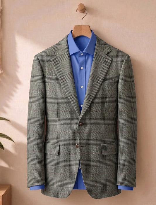 A men's two-button blazer in a gray and black windowpane plaid pattern, styled over a bright blue dress shirt and hanging on a wooden hanger against a warm beige wall.