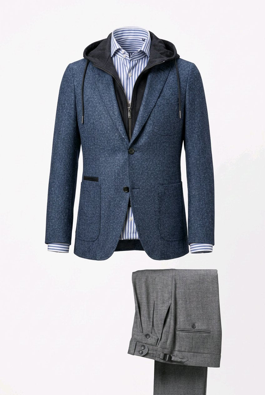 A men's two-piece suit set featuring a textured blue hooded blazer with a black zippered inner layer and striped shirt, paired with grey trousers, displayed on a mannequin against a white background.