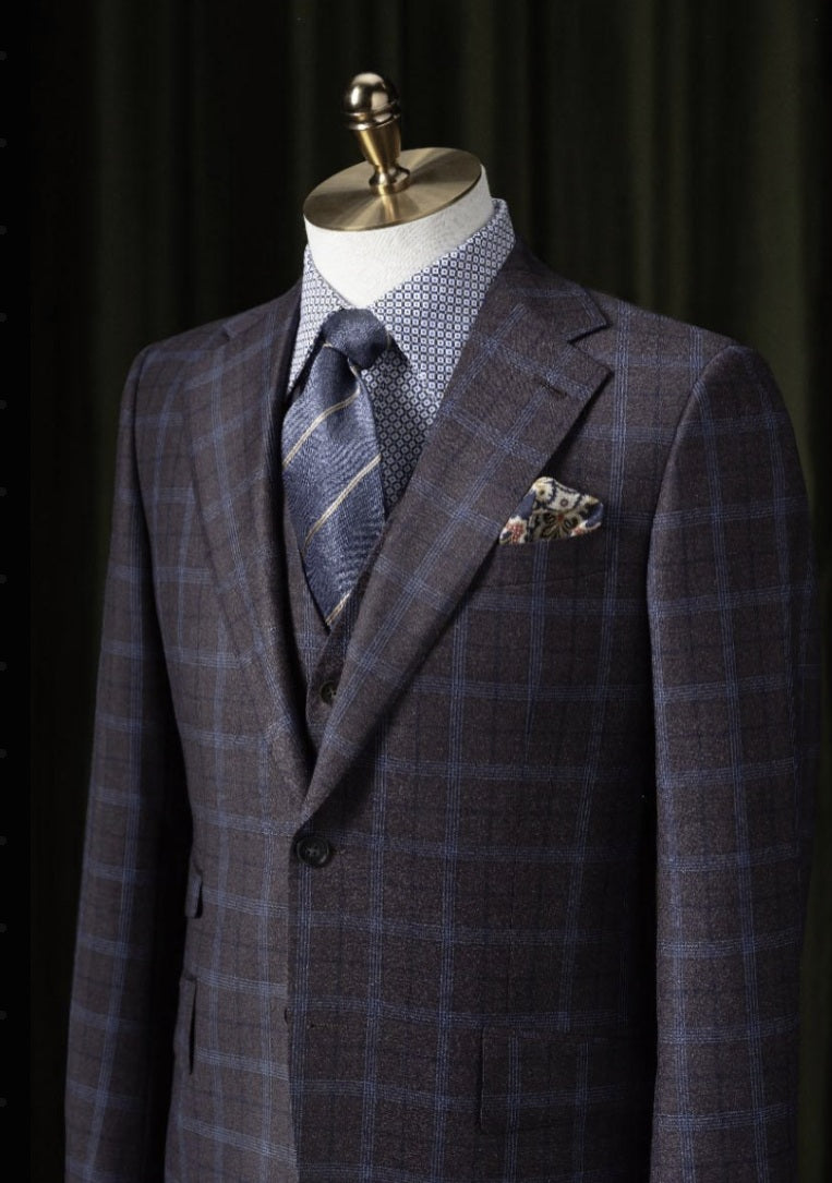 A purple and navy check patterned single-breasted jacket with notched lapels and a mandarin collar, displayed on a mannequin.