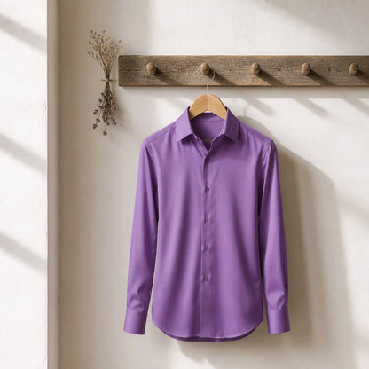 A purple long-sleeve button-up dress shirt hanging on a wooden hanger from a rustic wooden coat rack against a warm off-white wall.