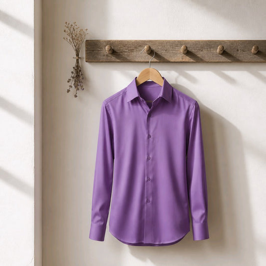 A purple long-sleeve button-up dress shirt hanging on a wooden hanger from a rustic wooden coat rack against a warm off-white wall.