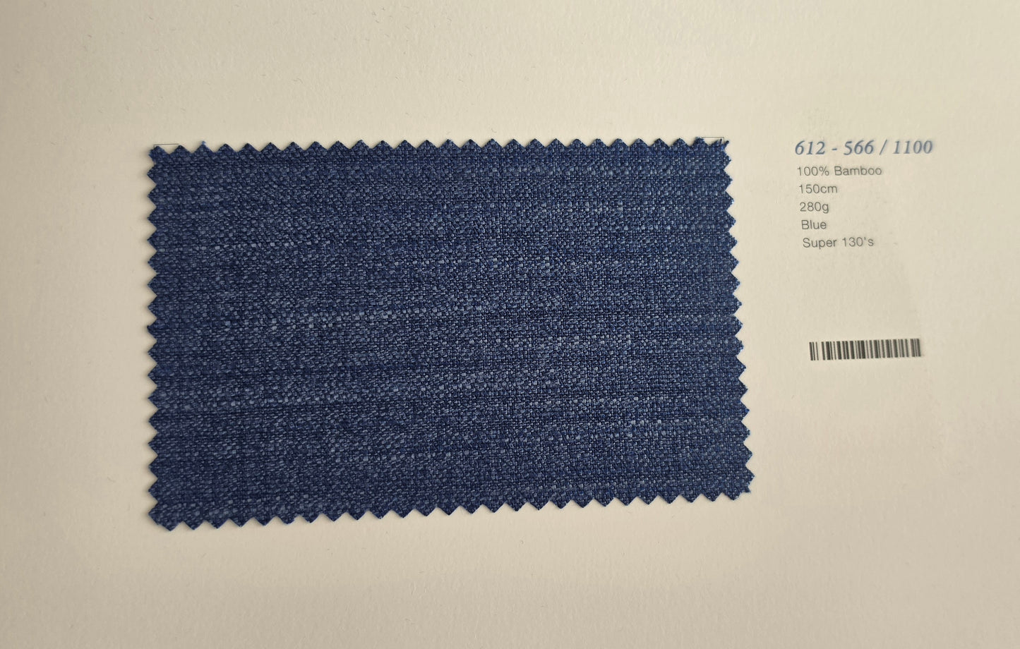 A rectangular blue fabric swatch with zigzag-cut edges displayed on a light beige background, next to printed text showing code 612-566/1100 and material details.