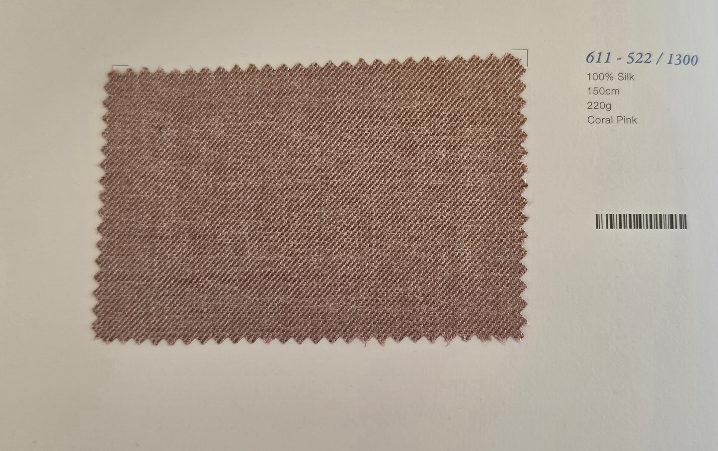 A rectangular coral pink silk fabric swatch with zigzag-cut edges, displayed on a light beige background with printed catalog details in the top right.