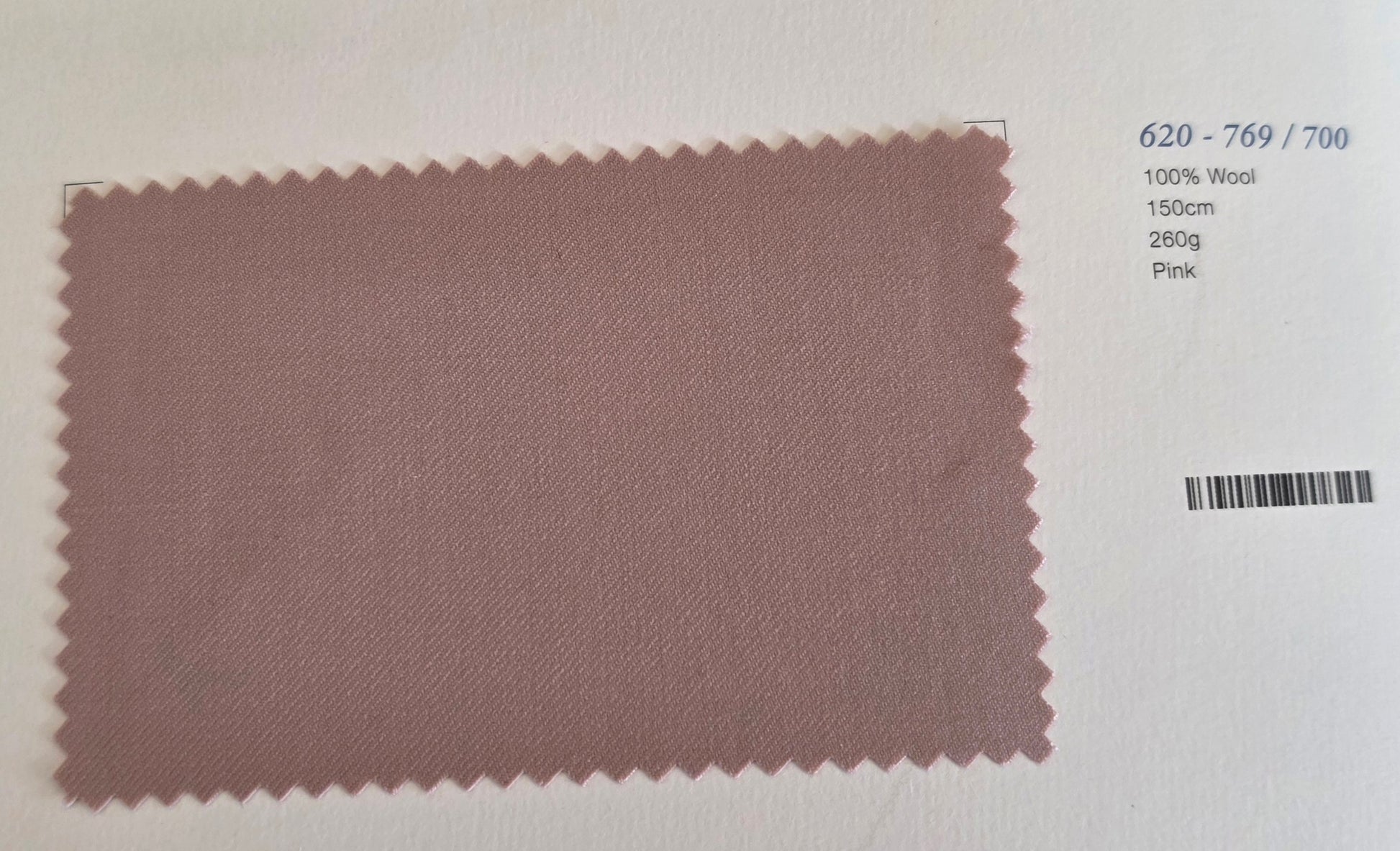 A rectangular fabric swatch of dusty pink wool with serrated edges, displayed on a white background with printed details on the right side.