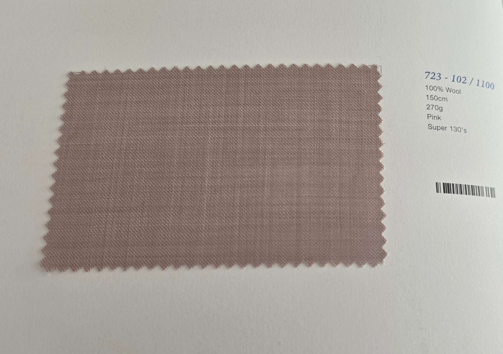 A rectangular fabric swatch with scalloped edges in a dusty pink/mauve color, displayed on a white background next to printed text identifying the material and color details.