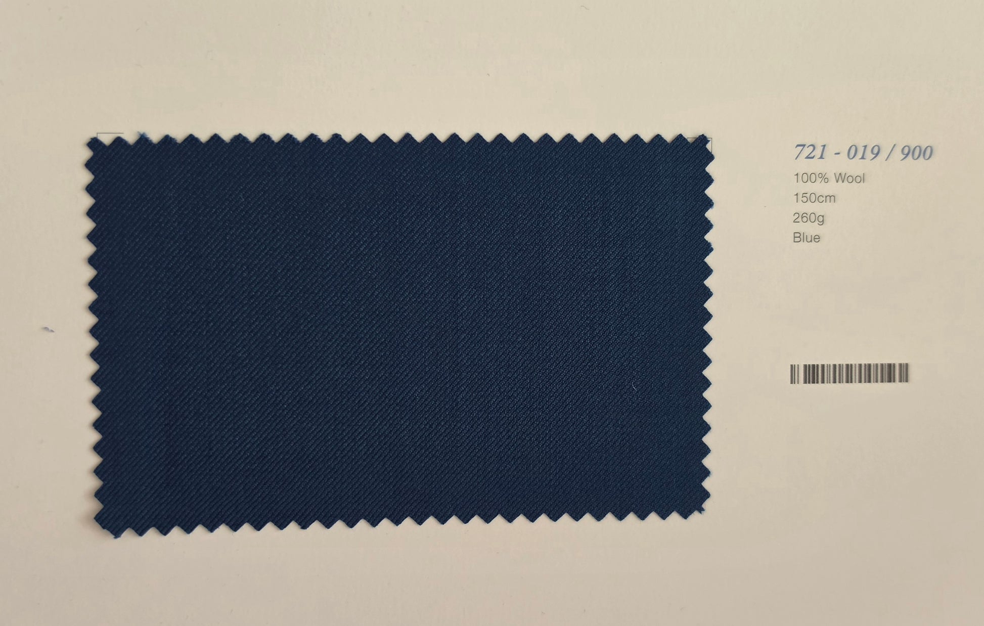 A rectangular fabric swatch with zigzag-cut edges in dark blue wool, shown on a light beige background with printed text reading '721-019/900', '100% Wool', '150g', '280g', and 'Blue'.