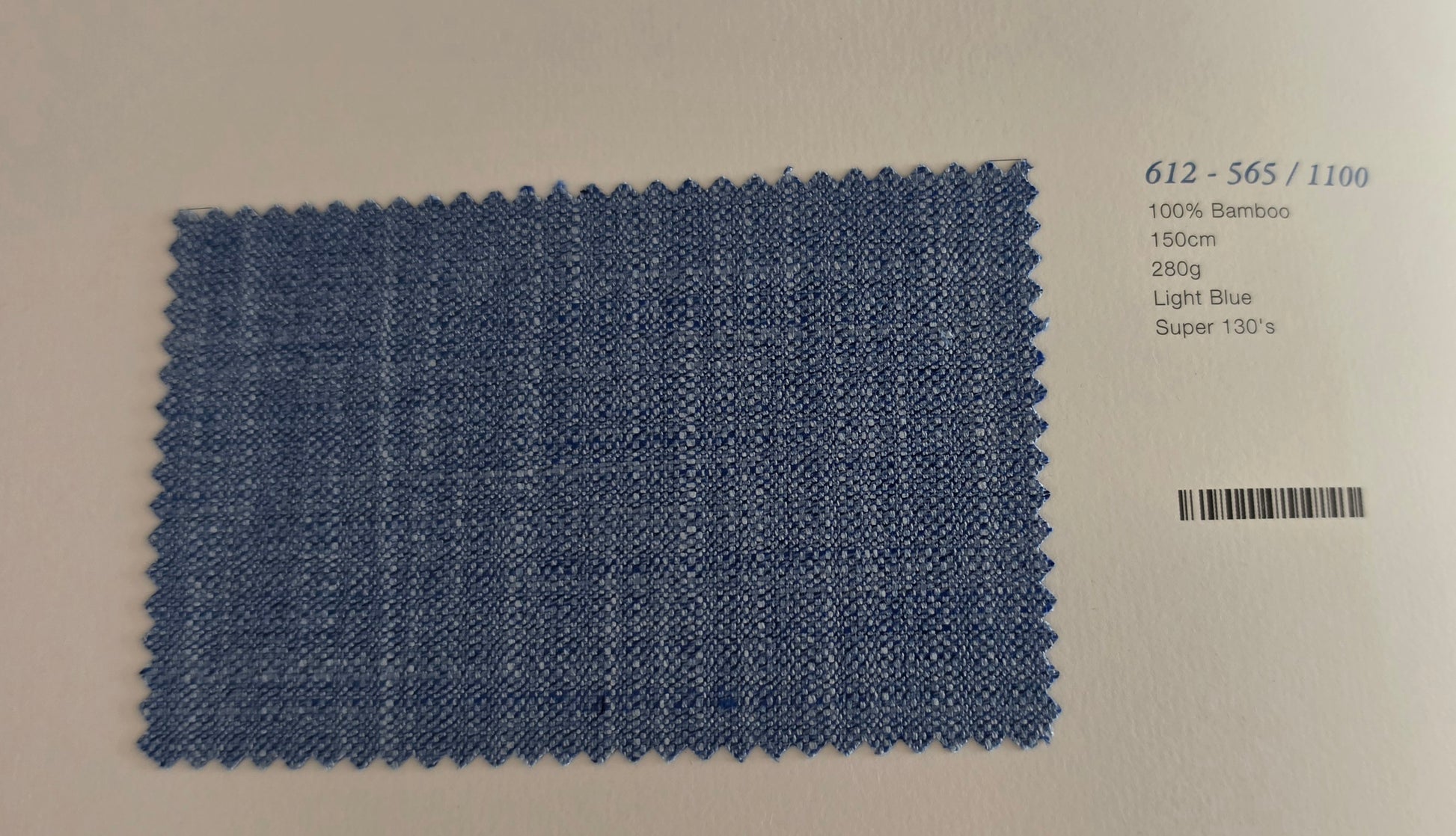 A rectangular light blue bamboo fabric swatch with a zigzag-cut edge, displayed on a white background next to printed product details including a barcode and color code 612-565/1100.