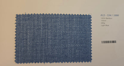 A rectangular light blue bamboo fabric swatch with zigzag-cut edges, displayed on a light beige background with printed text details on the right.