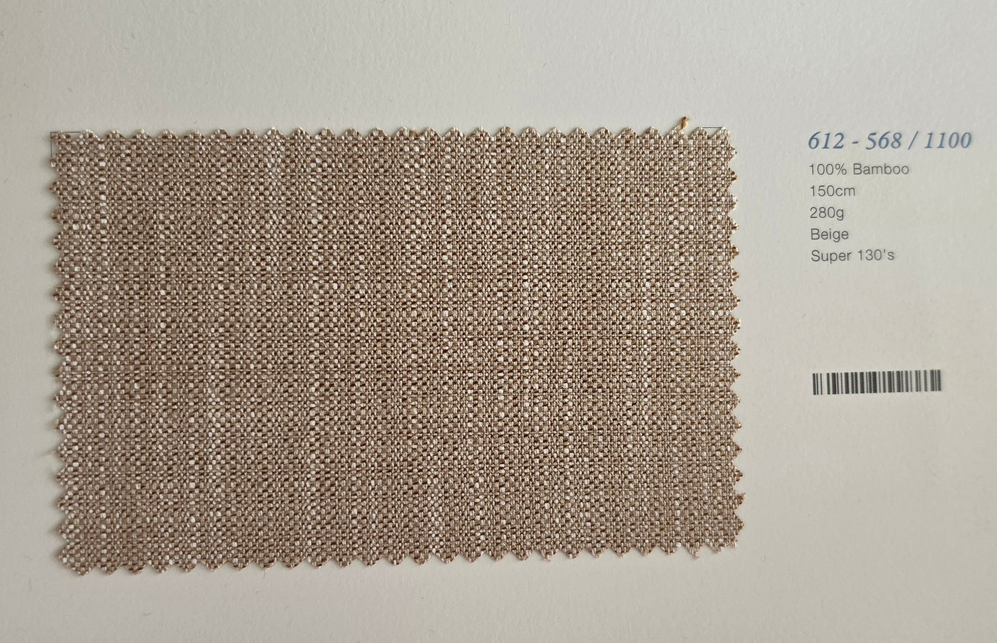A rectangular woven fabric swatch in a light beige/tan color with a textured basketweave pattern, displayed on a white background next to a barcode and product details text.