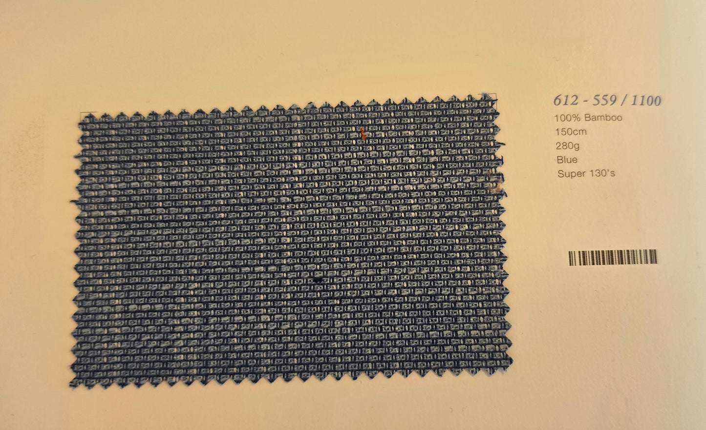 A rectangular woven fabric swatch in dark blue is displayed on a beige background with printed text to the right showing product details: '612-559/1100', '100% Bamboo', '1500m', '280g', 'Blue', and 'Super 130s'.