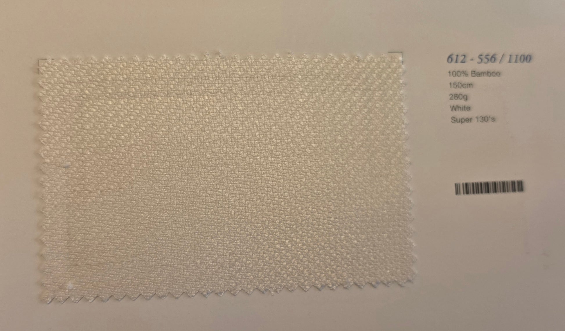 A square fabric swatch of off-white bamboo textured material with zigzag cut edges, displayed on a light background next to printed product details.