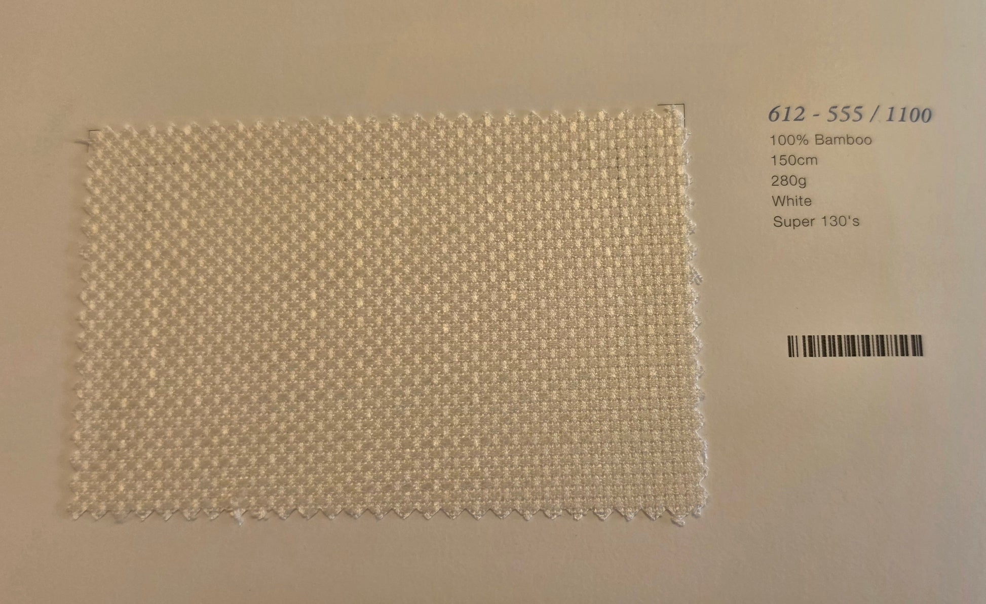 A square woven bamboo fabric swatch in white, displayed on a light beige background with printed product details on the right side.