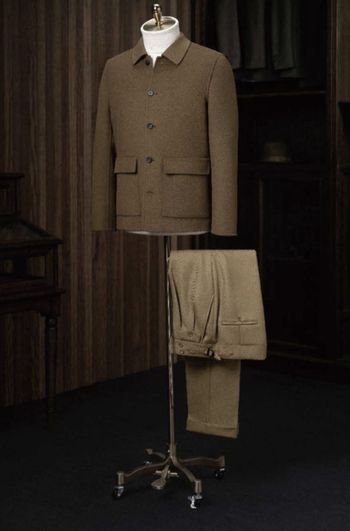 A tan casual jacket and tan twill trousers displayed on a mannequin, with the jacket featuring a high shirt collar, front pockets, and dark brown buttons. The trousers have a waistband and side adjusters.