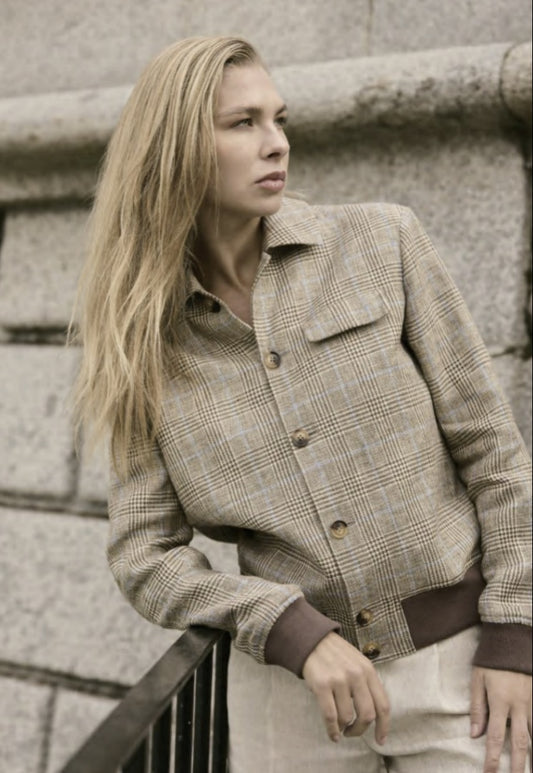 A woman wearing a beige and blue checkered single-breasted two-piece suit with a shirt collar and buttoned cuffs.