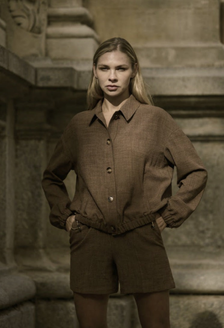 A woman wearing a beige single-breasted three-piece trouser suit with a slim fitted design and five-button fastening.