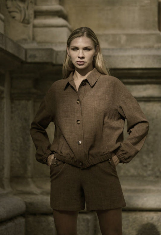 A woman wearing a beige single-breasted three-piece trouser suit with a slim fitted design and five-button fastening.