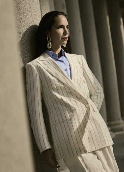 A woman wearing a white and black striped double-breasted two-piece suit with a peaked lapel, straight flapped pockets, and a single button fastening.