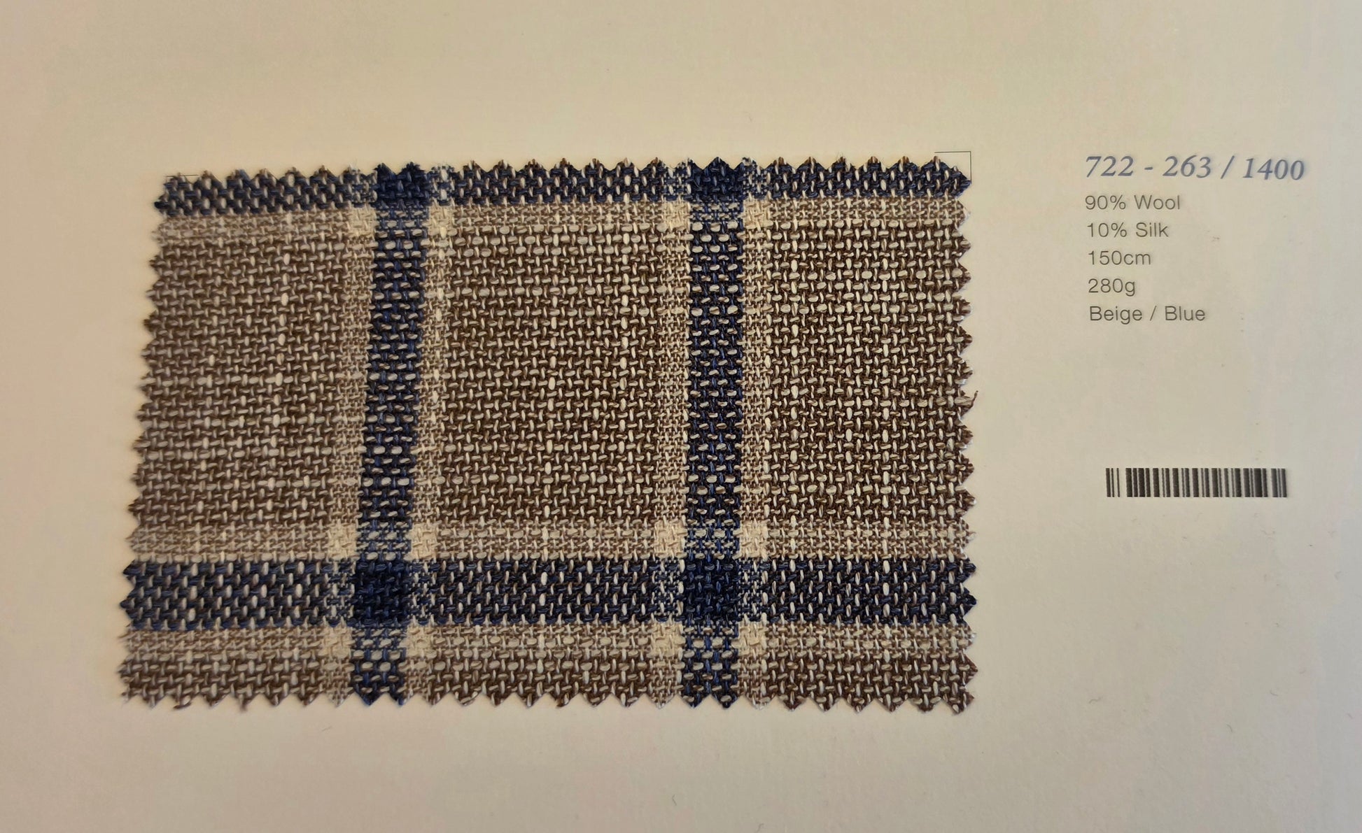A woven fabric swatch card showing a beige and blue plaid pattern, with text on the right indicating composition and barcode.