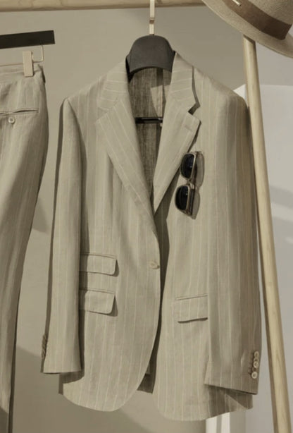 Beige pinstripe suit jacket on a hanger with sunglasses on top, against a neutral background.