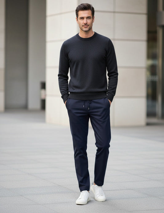 Man wearing a black sweater and navy pants with white shoes in an urban setting