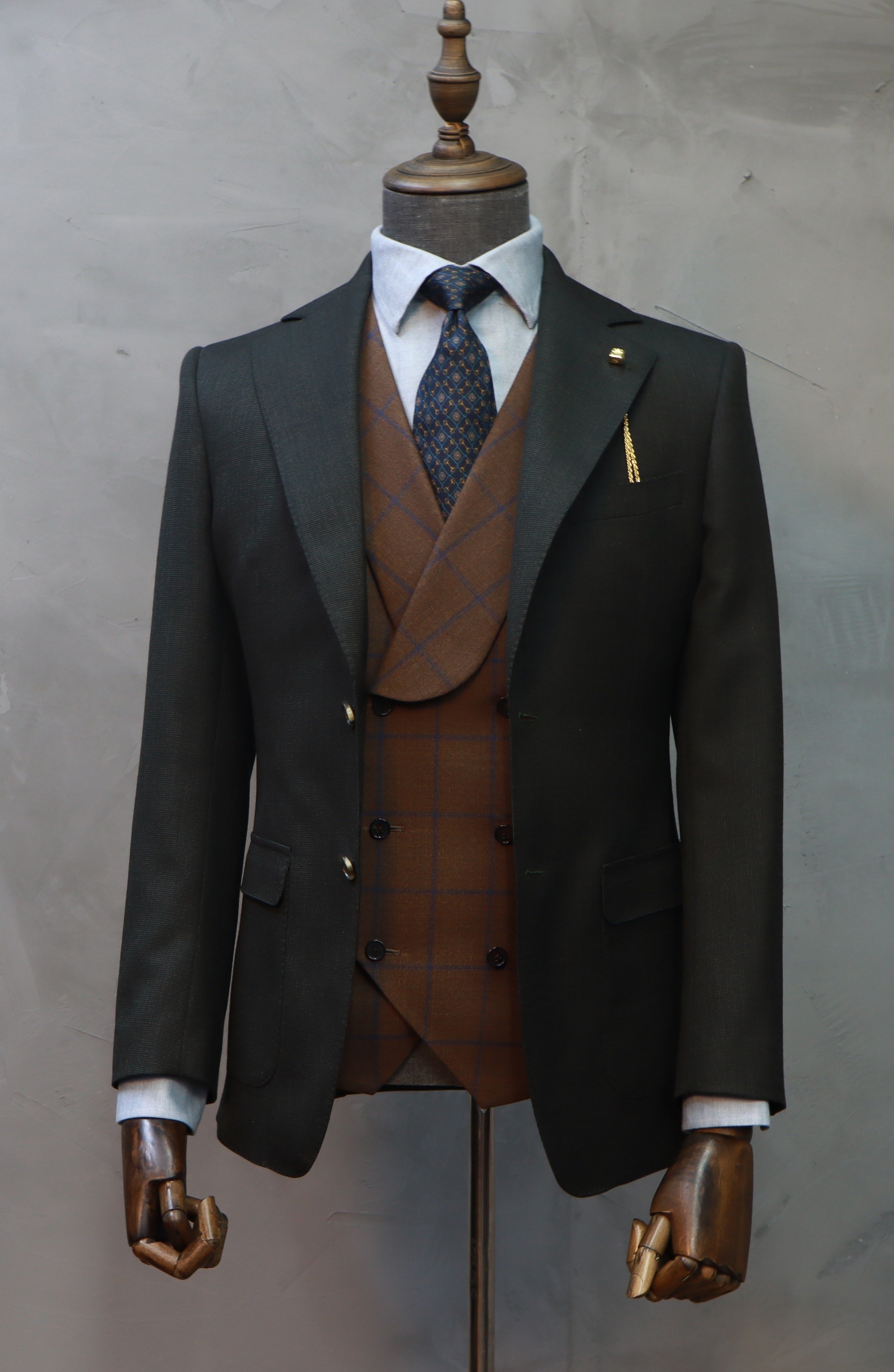 Black suit jacket with brown vest on a mannequin against a gray background