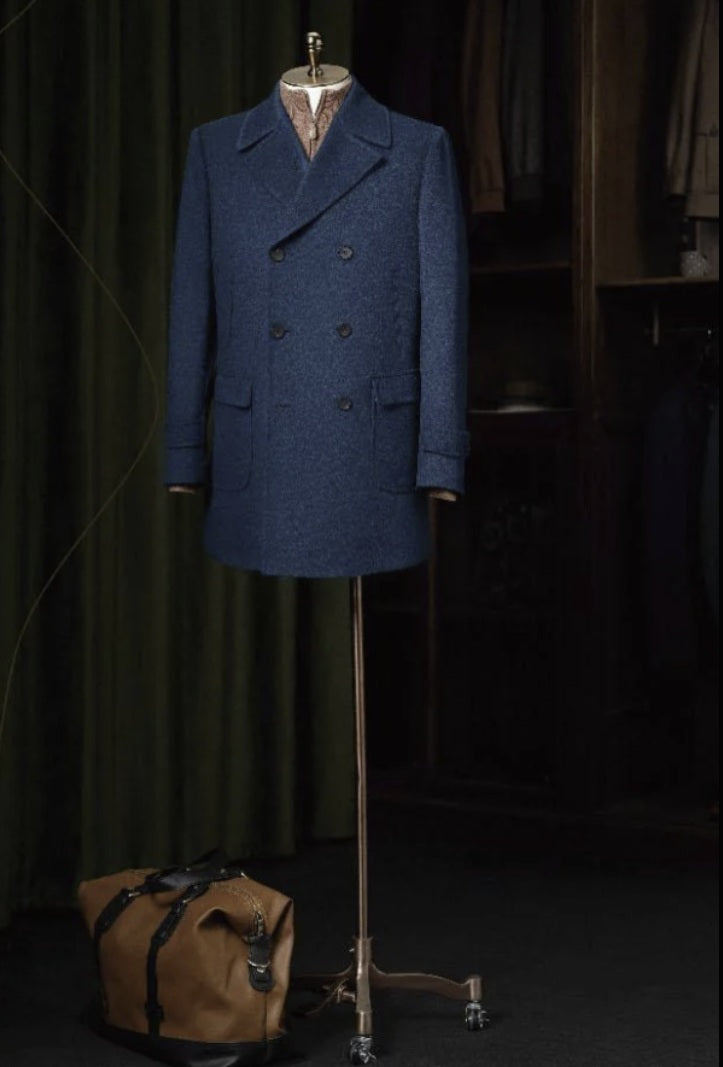 Blue coat on a mannequin with a brown bag on a dark background