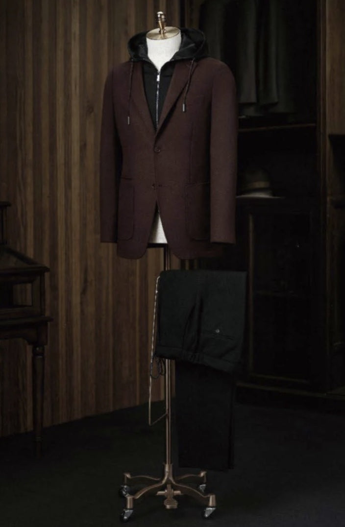 Brown coat on a mannequin against a wooden paneled wall.