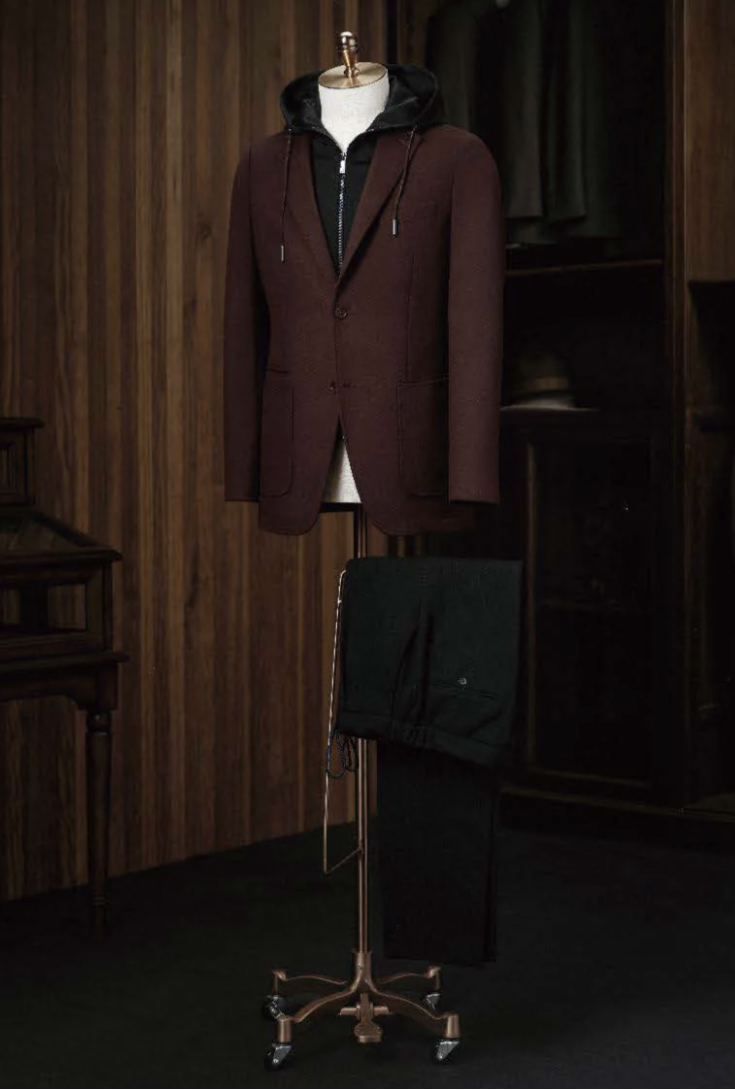 Brown coat on a mannequin against a wooden paneled wall.