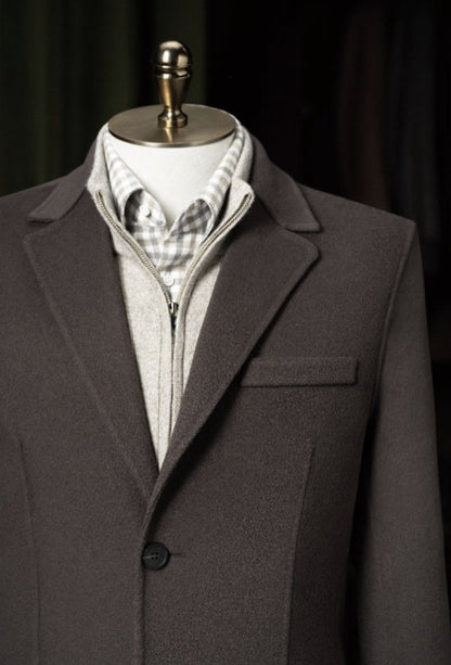 Brown suit jacket on a mannequin with a checkered shirt and gray vest against a dark background