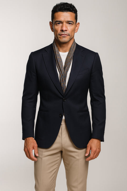 Man wearing a black blazer, white shirt, and beige pants against a plain background