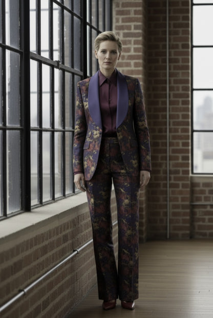 Woman in a patterned suit standing in a room with large windows and brick walls.