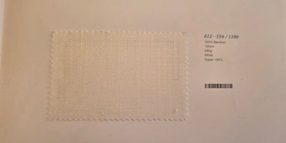 A square fabric swatch of off-white woven material with a zigzag stitched border, displayed on a light beige background next to printed product details including a barcode and text '612 - 554 / 1100'.