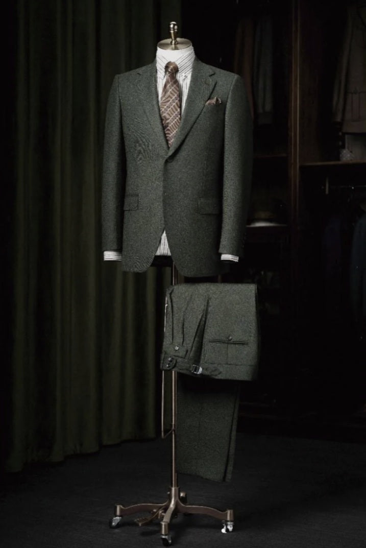 Green suit on a mannequin with a matching bag in a dark setting