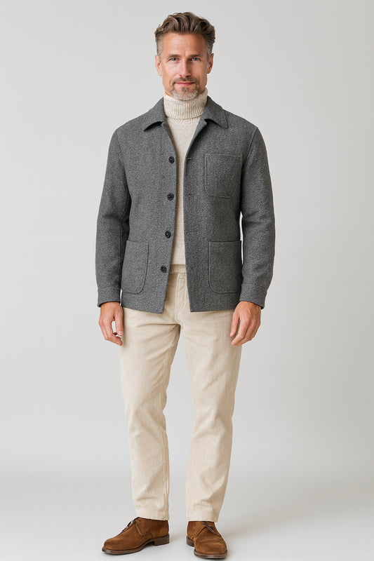 Man wearing a gray jacket, beige sweater, and pants on a white background