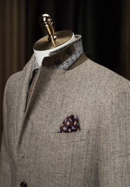 Grey textured suit jacket with patterned shirt and pocket square on a mannequin against a dark background