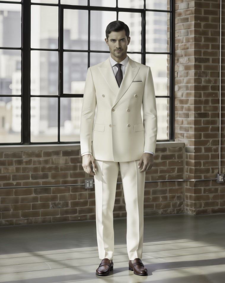 Man wearing a cream suit standing in front of a brick wall with large windows.