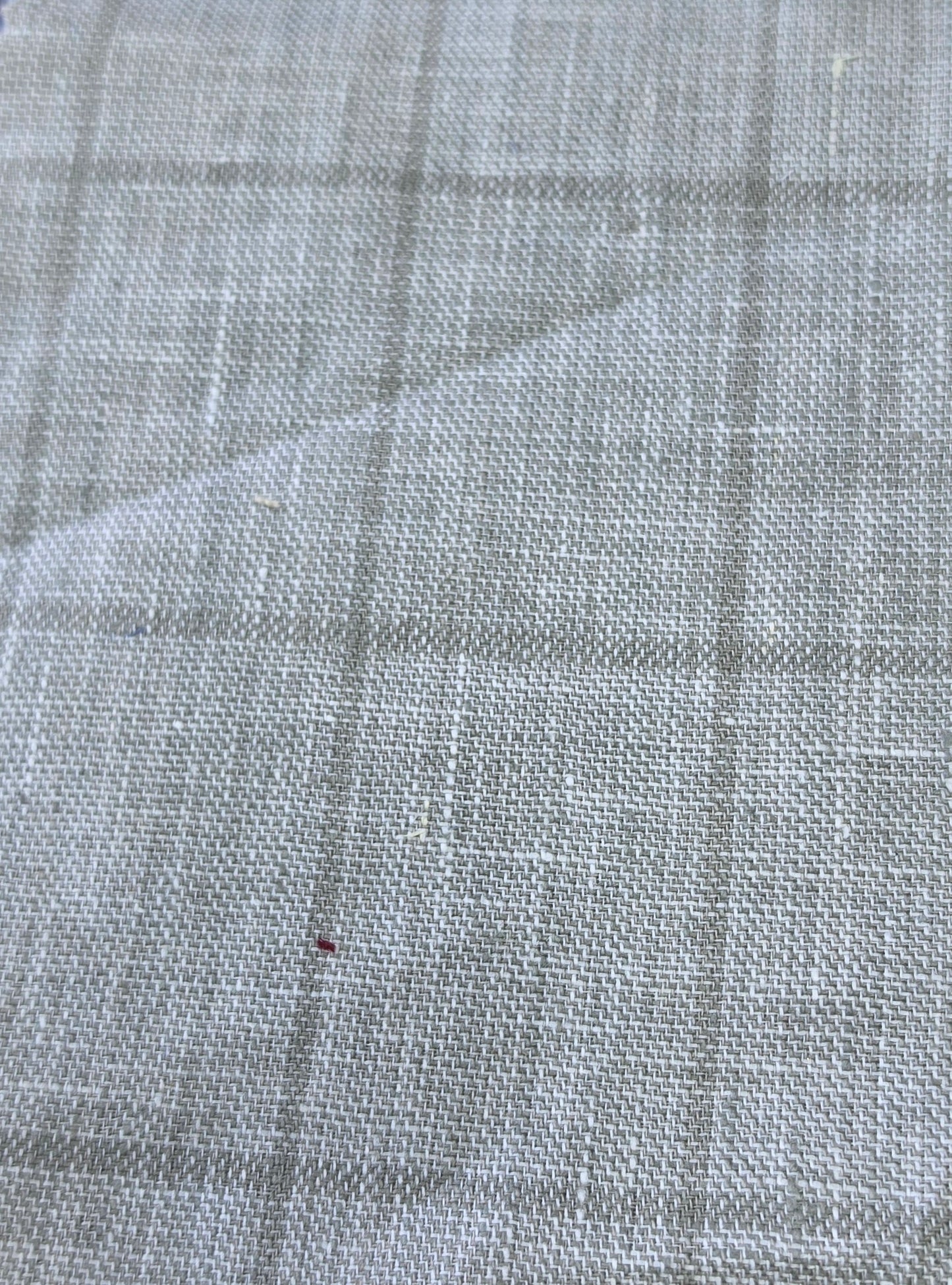 A close-up of a light gray woven fabric with a subtle plaid pattern, showing the texture and weave detail.