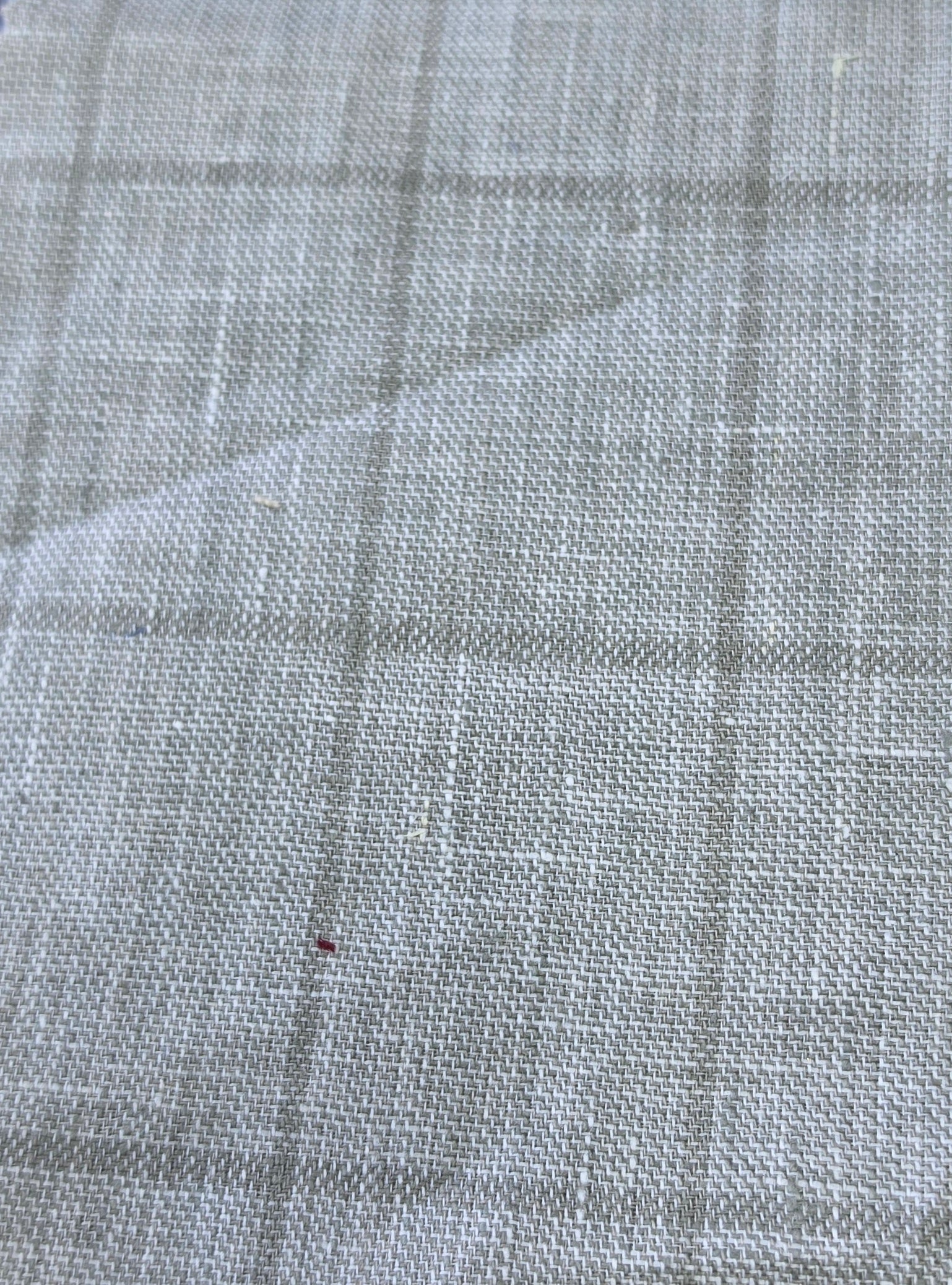 A close-up of a light gray woven fabric with a subtle plaid pattern, showing the texture and weave detail.